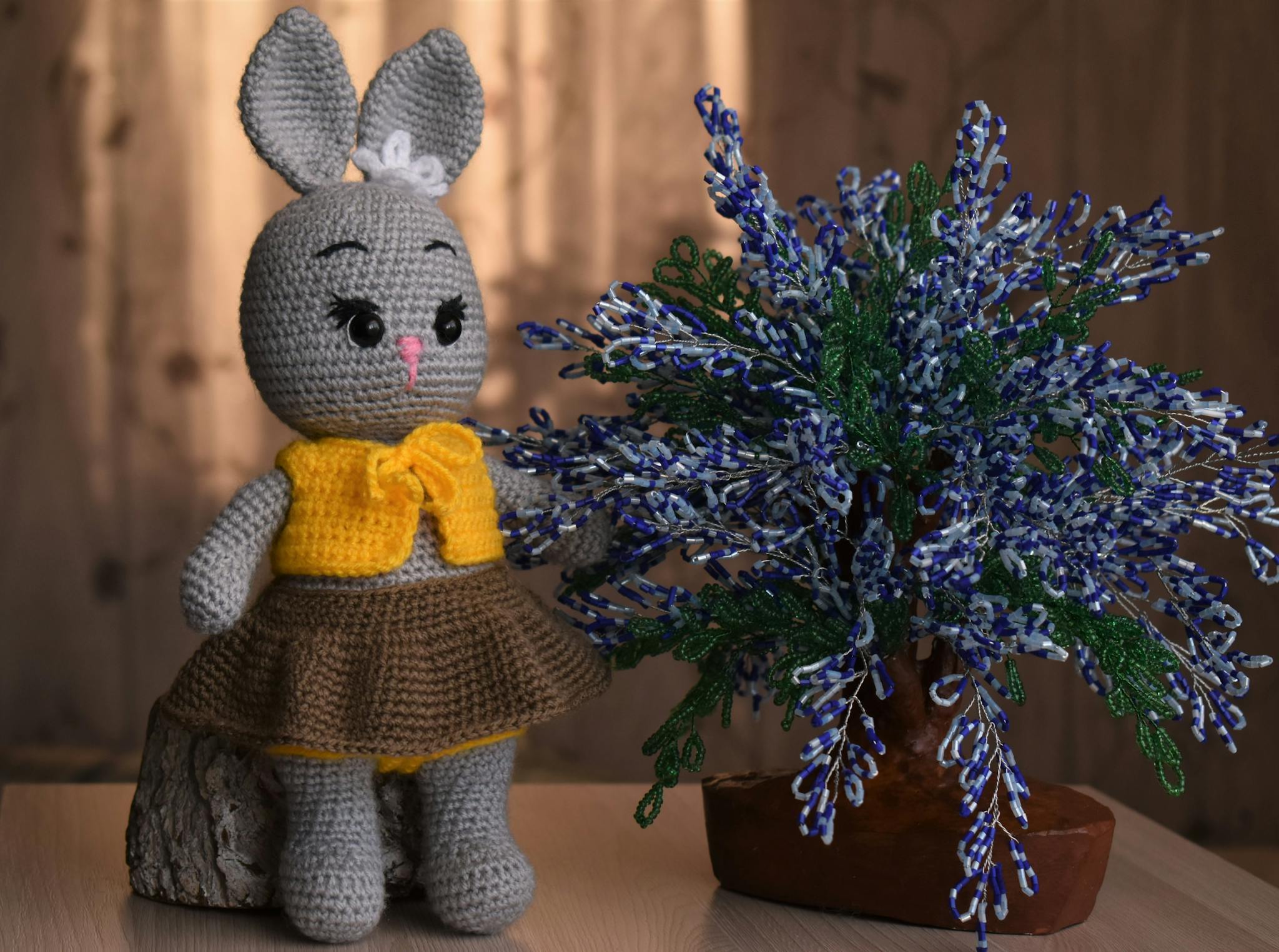 Adorable handmade crochet bunny toy next to a decorative plant in a cozy setting.