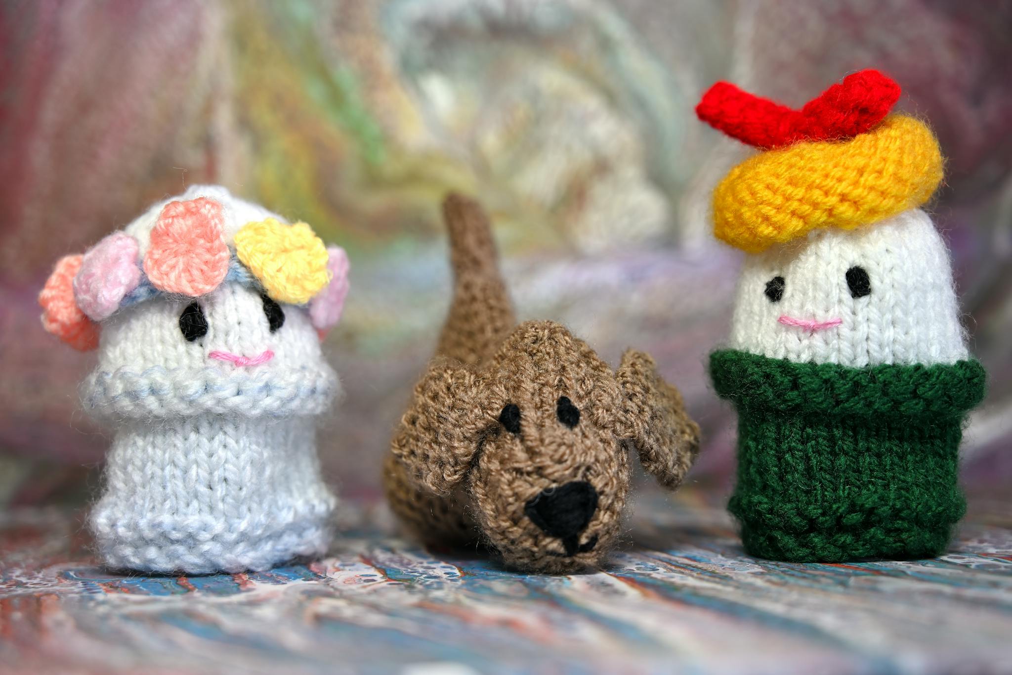 Handmade knitted toys including a dog and colorful dolls with intricate designs.