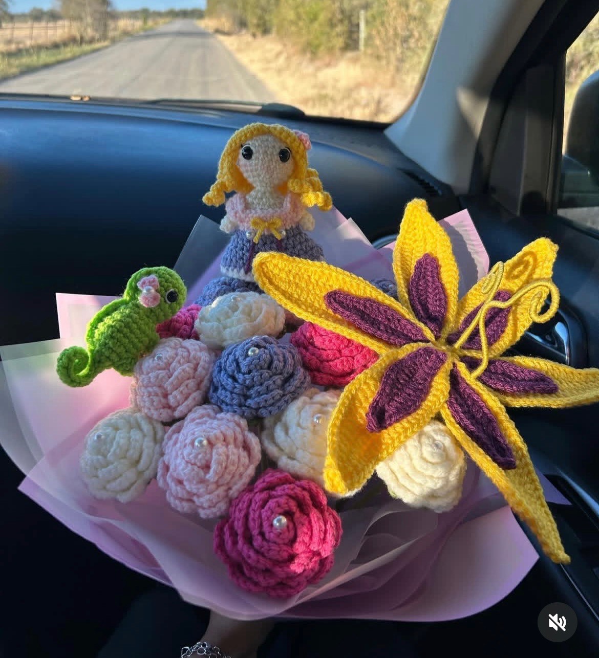 A crochet bouquet of flowers, a small doll, and a small chameleon